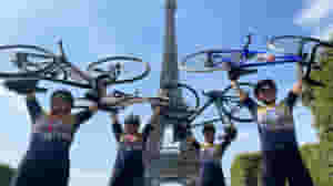 Riders holding up their bikes in front of the Eiffel Tower