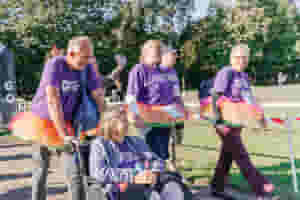 Several people walking and one person in a wheelchair, wearing tutus and flower crowns (1)