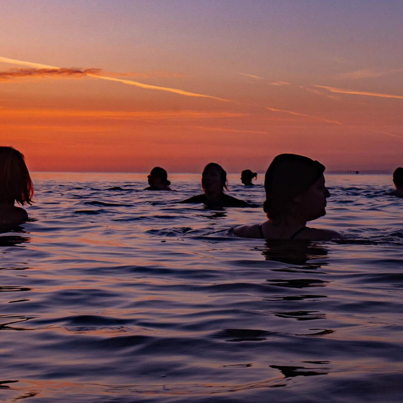 An outdoor swimming community encouraging people to get in the sea just before the sun rises, at Penarth Seafront in South Wales.
